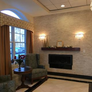 A cozy lounge area with comfortable chairs and a modern fireplace, illuminated by soft wall sconces.