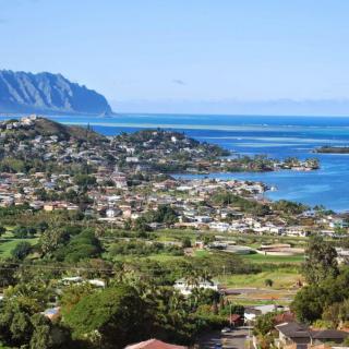 A picturesque view of a coastal town with mountains in the background and the ocean stretching into the horizon.