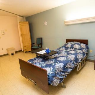 A simple hospital room with a single bed and basic furnishings.