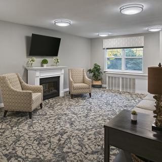 A cozy living room with a fireplace and armchairs arranged around it.
