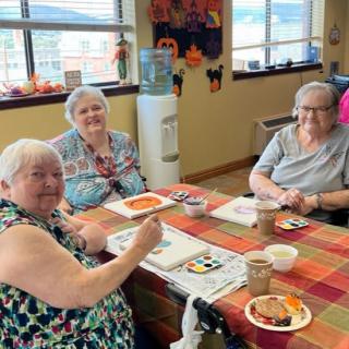 A group of seniors engaged in a painting activity at a community center.