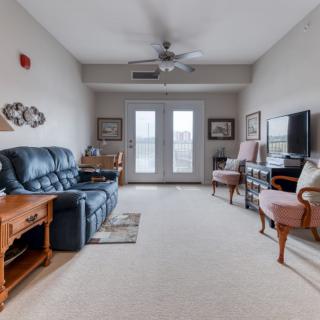 A cozy living room with a leather sofa, television, and large windows.