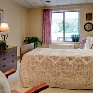 A cozy bedroom with a large bed, dresser, and window allowing natural light in.