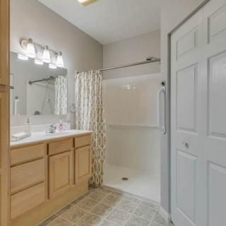 A well-lit bathroom featuring a shower with a curtain, a vanity with a mirror, and wooden cabinets.