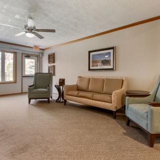 A cozy living room featuring a sofa, armchairs, and a ceiling fan.