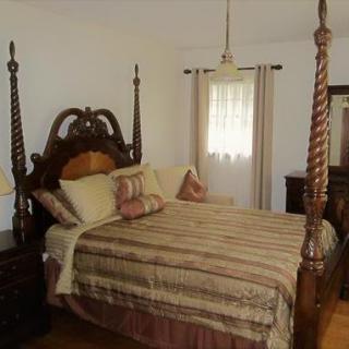A traditionally styled bedroom featuring a four-poster bed with striped bedding and ornate wooden furniture.