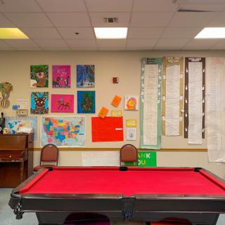 A vibrant game room featuring a red pool table and colorful art on the walls.