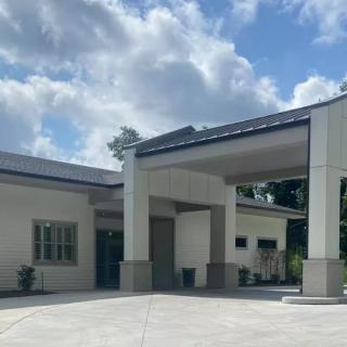 A modern building with an extended driveway under a partly cloudy sky.