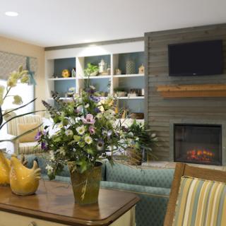 A cozy living room featuring elegant furniture, vibrant flowers, and a warm fireplace.