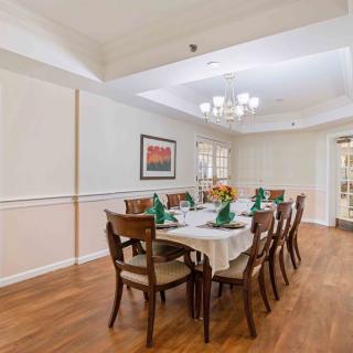 A well-appointed dining room with a long table, multiple chairs, and a chandelier hanging above.
