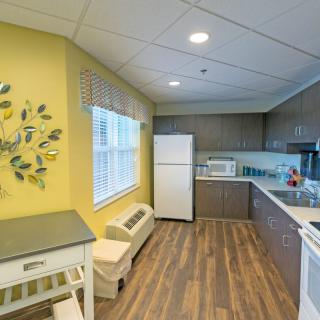 A modern kitchen with yellow walls, wood flooring, and white appliances.