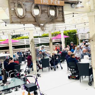 A lively outdoor cafe setting with people enjoying their meals and conversations under a shaded patio.