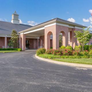 A brick church building with an arched entrance and landscaped surroundings.