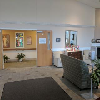 A reception area with comfortable seating, plants, and an entrance to another room.