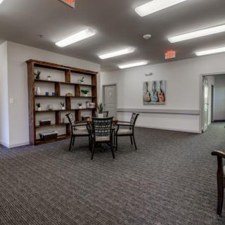 A quiet indoor room with a table, chairs, and a bookshelf.