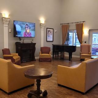 A cozy living room with a TV, seating area, and piano.