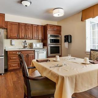 A cozy kitchen and dining area with wooden cabinets, featuring a dining table set for two.