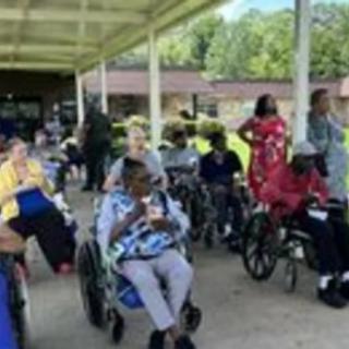 A group of people in wheelchairs enjoying time outdoors at a nursing home.
