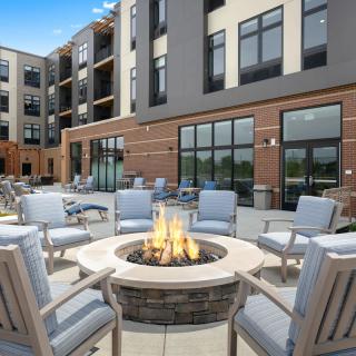 A modern apartment complex featuring an outdoor seating area around a fire pit.