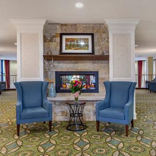 A cozy seating area with two blue chairs flanking a fireplace in a well-decorated lobby.