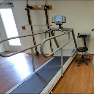 A rehabilitation treadmill with supportive rails in a physical therapy room.