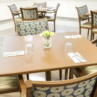 A cozy dining area with neatly arranged tables and chairs, featuring floral centerpieces.