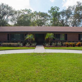 A single-story suburban house with a well-maintained front yard and surrounding trees.