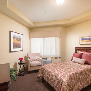 A cozy bedroom with a single bed, armchair, and artwork on the walls.