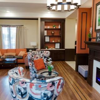 A modern living room featuring a colorful sofa, fireplace, and built-in bookshelf with decor items.