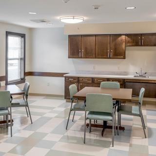 A modern kitchen and dining area with tables, chairs, and wooden cabinets.
