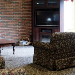A cozy living room with a television, armchairs, and a brick wall.