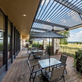 A cozy outdoor patio area with tables and chairs under a pergola, offering a scenic view.