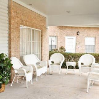 A cozy porch with white wicker furniture and a potted plant.