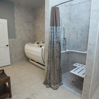 A modern bathroom featuring a bathtub and a walk-in shower with a curtain and built-in seat.