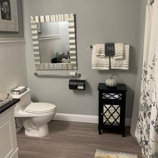 A modern bathroom with a decorative mirror, toilet, and storage cabinet.