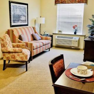 A cozy living room with a striped sofa, patterned armchair, and a small dining area.