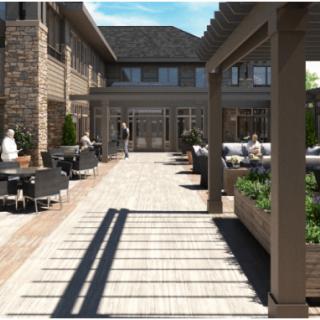 A spacious outdoor patio with seating and a pergola, surrounded by a brick building.