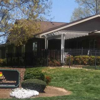A building entrance surrounded by landscaped greenery with a visible sign and awning.