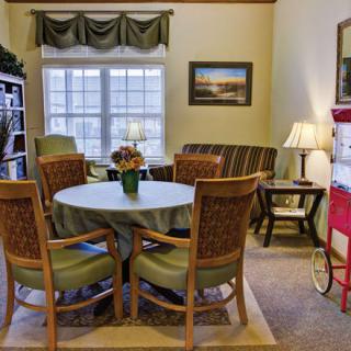 A cozy living and dining area with a round table, chairs, and a sofa near a window.