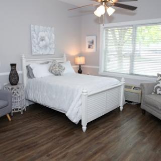 A serene and modern bedroom featuring a white bed, cozy seating area, and ample natural light.