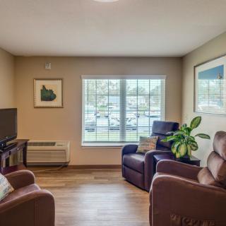 A cozy living room with comfortable chairs, a television, and a large window allowing natural light.