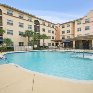 An inviting outdoor swimming pool surrounded by a hotel building with palm trees.