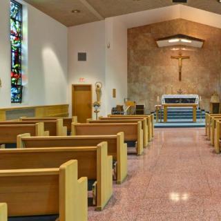 Interior view of a church showing pews, altar, and stained glass.