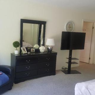 A cozy bedroom setup featuring a dresser with a mirror and a TV stand.