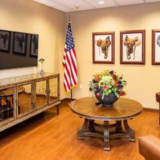 A well-decorated office space featuring an American flag, floral arrangement on a round table, and framed artwork on the wall.