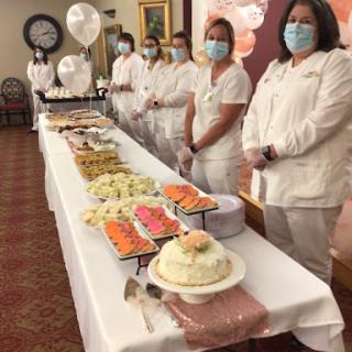Healthcare staff present at a celebration with a variety of delicious food and desserts.