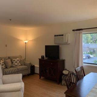 A cozy living room featuring a sofa, television, dining table, and floor lamp.