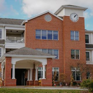 A modern brick residential building featuring a prominent clock on its facade.