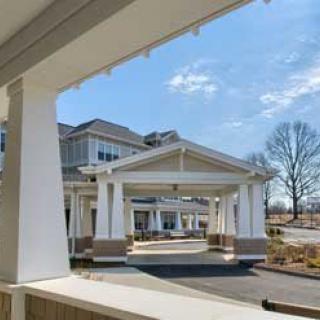 A modern building entrance with large columns and a covered porch under a clear blue sky.