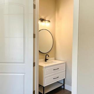 A sleek and modern bathroom vanity featuring a round mirror and stylish lighting.
